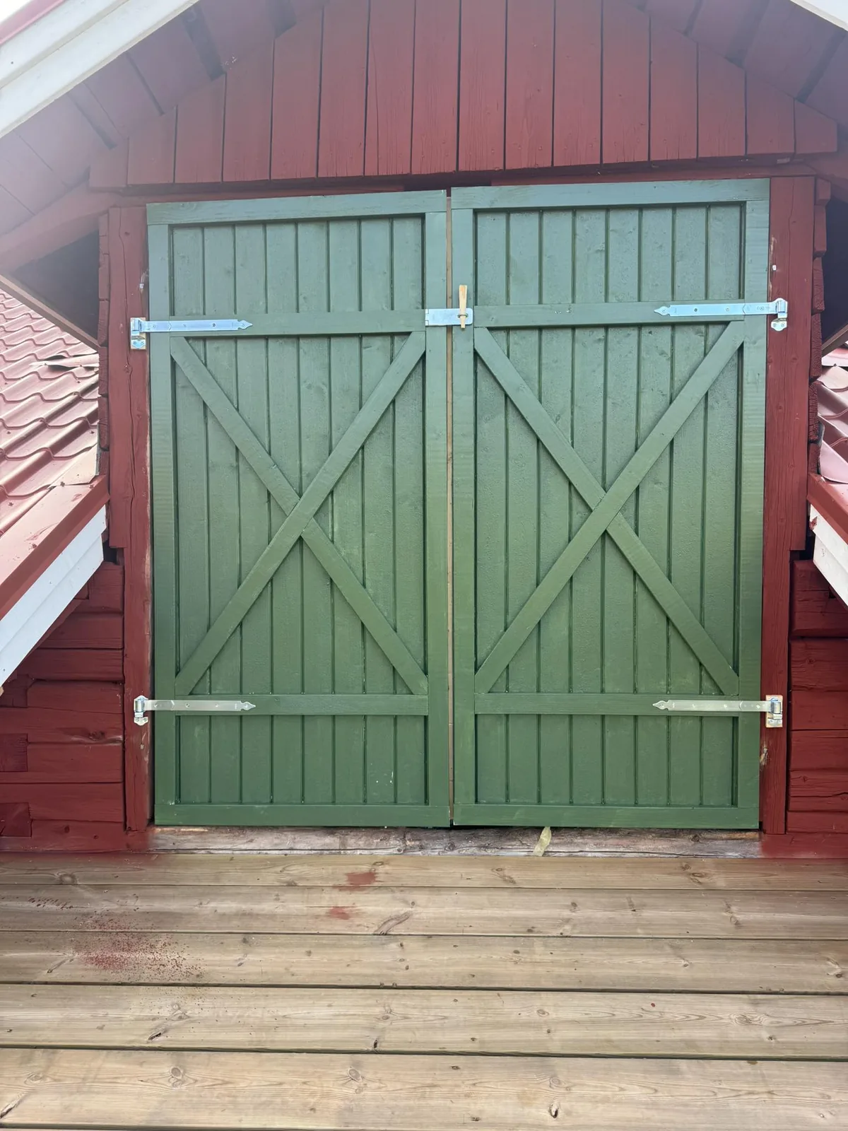 Grön dubbelport på ladugård, träarbete av Norderö Byggtjänst