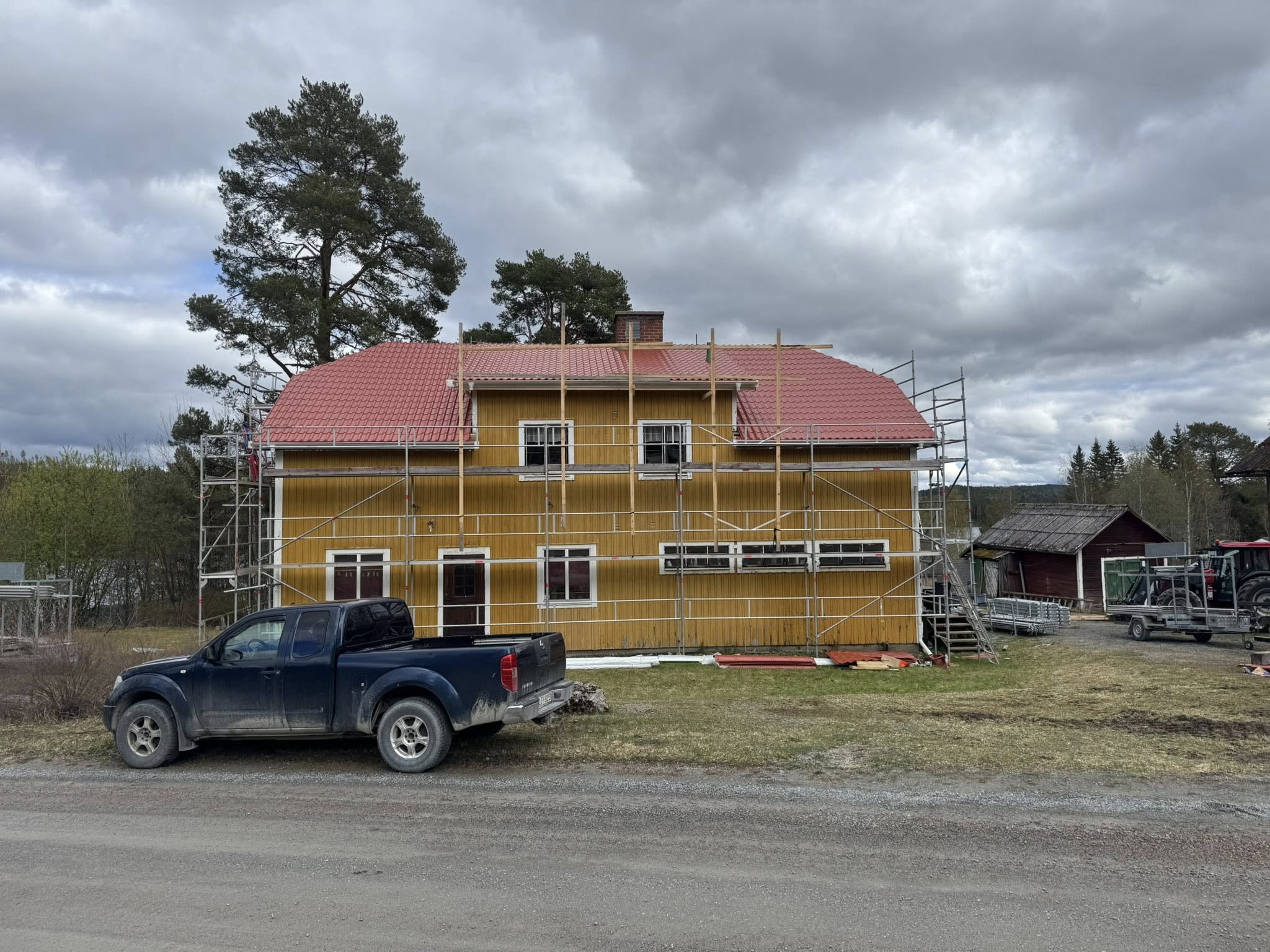 Takrenovering på gult trähus med byggställning