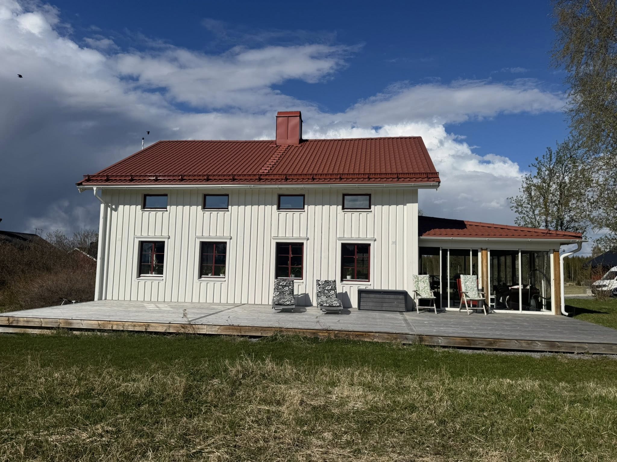 Vitt trähus med rött tak och uteplats — fasad- och uterumsprojekt av Norderö Byggtjänst